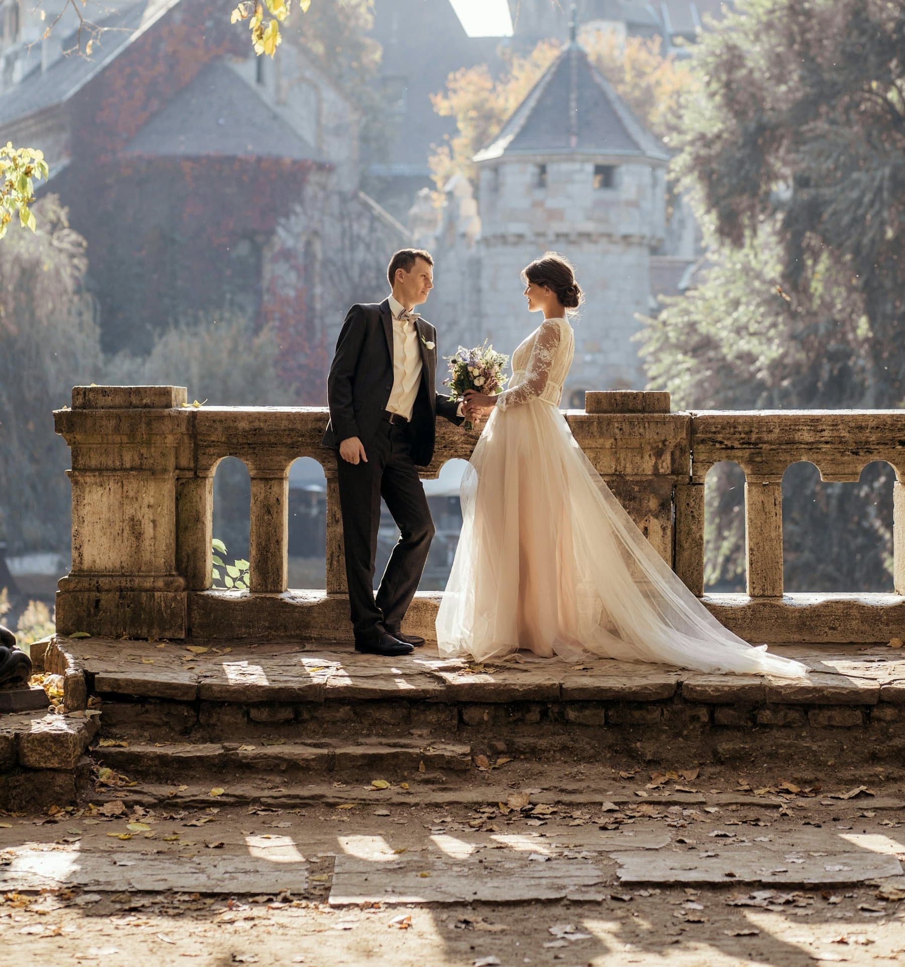 A bride and groom facing each other on a stone terrace in golden-hour light